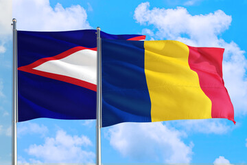 Romania and American Samoa national flag waving in the windy deep blue sky. Diplomacy and...