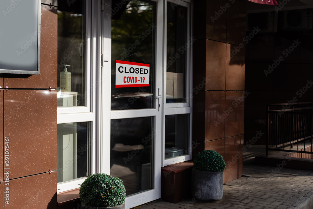 Poster close-up on a red closed sign in the window of a shop displaying the message 