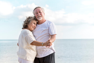 Happy asian senior retired couple dancing with relax smiling  on sea beach, elder man and woman enjoying with retired vacation. Health care, Family outdoor lifestyle concept