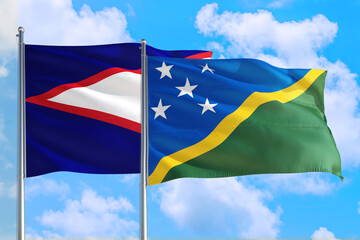 Solomon Islands and American Samoa national flag waving in the windy deep blue sky. Diplomacy and international relations concept.