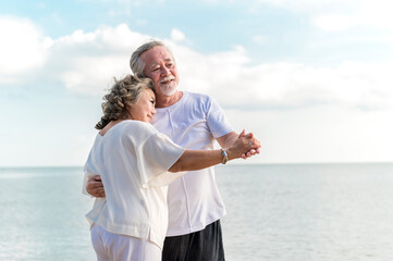 Fototapeta na wymiar Happy asian senior retired couple dancing with relax smiling on sea beach, elder man and woman enjoying with retired vacation. Health care, Family outdoor lifestyle concept