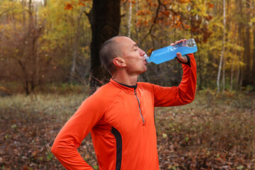 Male runner, athlete, drinks isotonic, energy drink after a hard workout in the open air. Sports...