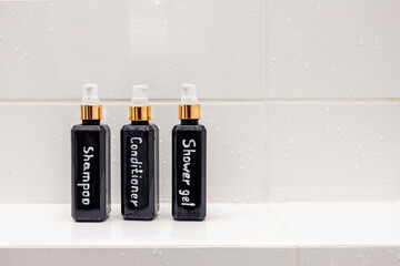 Three bottles with bathroom essentials over white tile