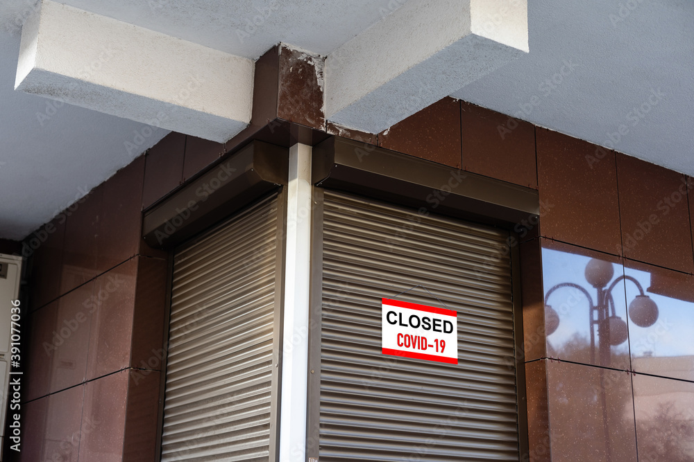 Poster close-up on a red closed sign in the window of a shop displaying the message 