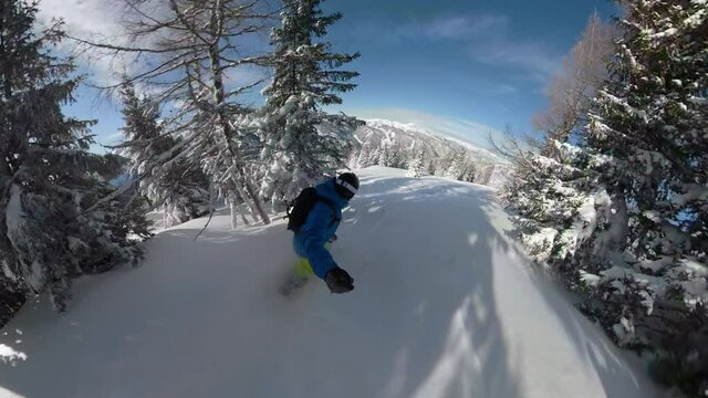 SELFIE, 360VR: Extreme snowboarder is carving fresh powder snow while riding through a spruce forest in the picturesque Julian Alps. Young male tourist rides his powder board down a snowy mountain.