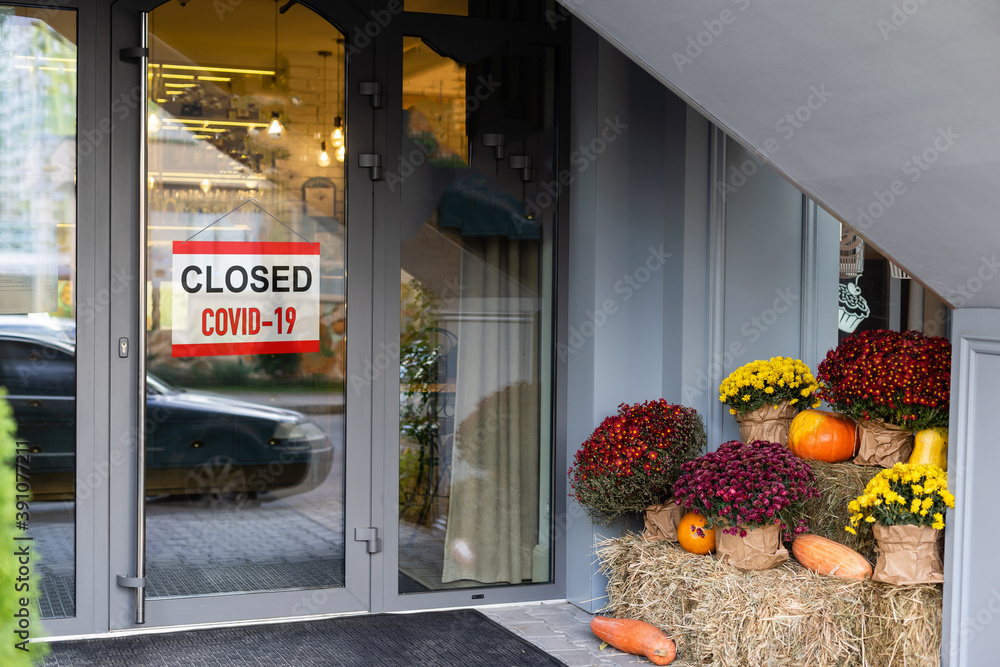 Poster close-up on a red closed sign in the window of a shop displaying the message 