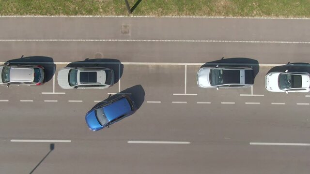 AERIAL, TOP DOWN: Unrecognizable person tries to parallel park their car into a tight roadside parking spot. Driver attempts to back their vehicle into a parking space at the side of the street.