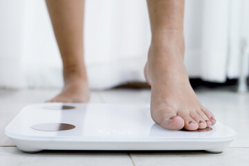 feet standing on electronic scales for weight control. Measurement instrument in kilogram for a diet control.