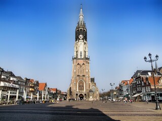 The Nieuwe Kerk - New Church. Protestant church in the city of Delft in the Holland. The building is located on Delft Market Square - Markt. Cloudless blue sky and people walking around.