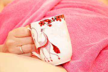 Woman with a cup of coffee in pink towel