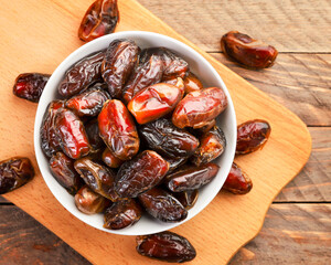 Dates fruit in a plate on a wooden background. The view from top