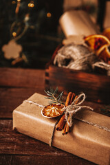  Christmas gift wrapped in kraft paper and decorated with eco-friendly materials on a wooden background, vertical photo