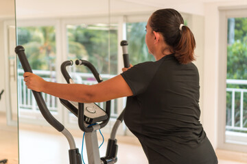 Fototapeta na wymiar Woman performing workout on elliptical trainer at home
