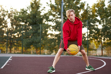 Obraz premium caucasian teenager boy perform tricks with a basketball on the sports ground. outdoors