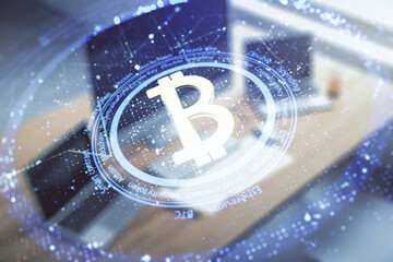Double exposure of creative Bitcoin symbol hologram and modern desk with computer on background. Mining and blockchain concept