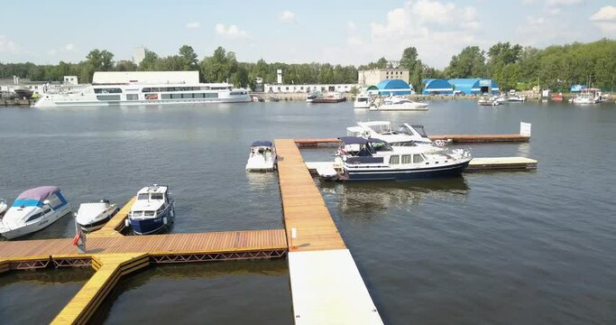 4K high quality calm windless bright summer morning aerial video of Moscow Channel yacht club embankment, green trees, wooden pier and shore with moored anchored boats and yachts near Moscow, Russia