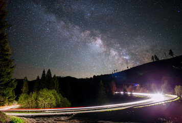 Fototapeta premium Milky way over a road light up by a car 