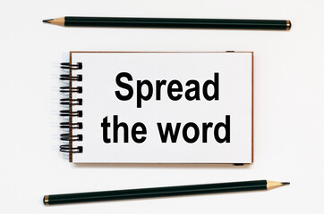 WHITE SPIRAL NOTEBOOK, TWO PENCILS WITH TEXT SPREAD THE WORD