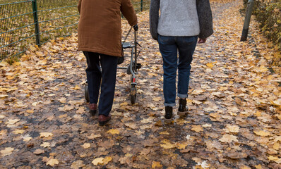 Elderly woman taking a walk with granddaughter with the help of a walker in winter