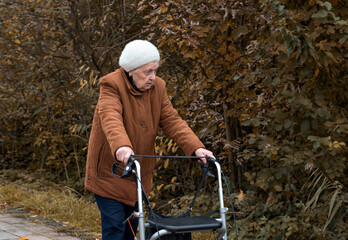 Elderly woman taking a walk in autumn with walker aid to enjoy fresh air