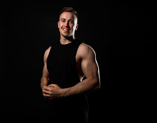 Handsome and fit bodybuilder posing on black background in workout gear