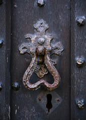 Old metal door handle knocker and key hole on a rough wooden background