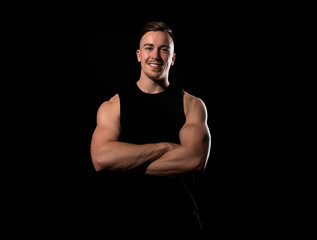 Fototapeta na wymiar Handsome and fit bodybuilder posing on black background in workout gear