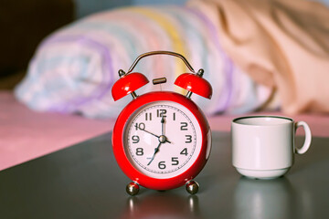 Red alarm-clock in the badroom, morning time, selective focus.