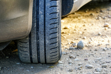 Selective focus of typical summer tire on gravel road with copy space