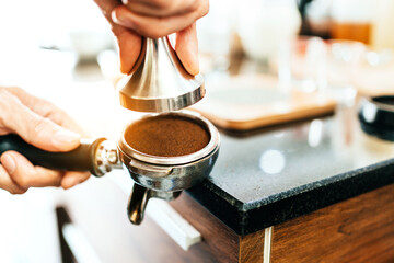 Close-up ground coffee bean in metal filter with handle holding by woman hand.Coffee making classes for entrepreneurs to start small businesses.