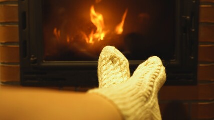 Woman is resting by the fireplace in the house.