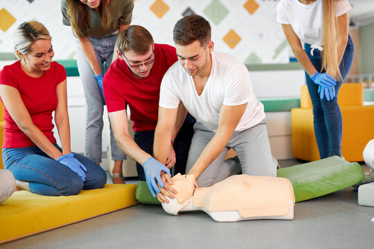 CPR class with young caucasian instructors speaking and demonstrating help first aid, cpr mannequin on the floor