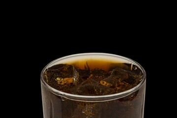 Close up view of top of full glass of soda with ice cubes isolated on black background. Unhealthy drinks concept. Health concept. Beverage concept.