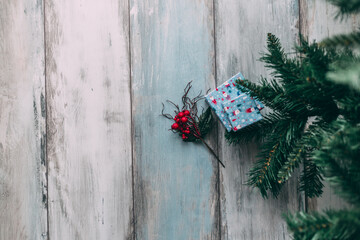 Gift  boxes and artificial red berries under Christmas tree, flat lay with copy space left