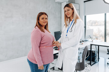 Nutritionist measuring waist of overweight woman in weight loss clinic.