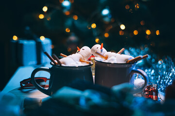 a mug with hot chocolate on a wooden table with a marshmallow man who is resting in a mug