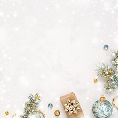 Christmas snowy white background with gift, fir twigs, gold blue decorations. Copy space. Christmas frame.