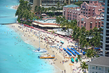 Tourists enjoying vacationing on world famous Waikiki Beach in front of the iconic Royal Hawaiian...