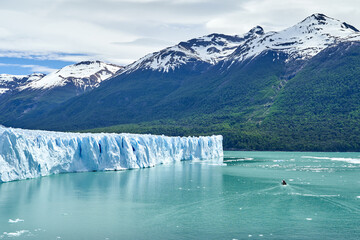 Blue ice of Perito Moreno Glacier in Glaciers national park in Patagonia, Argentina with turquoise water of Lago Argentino in the foreground, dark green forests and sow covered mountains of the Andes