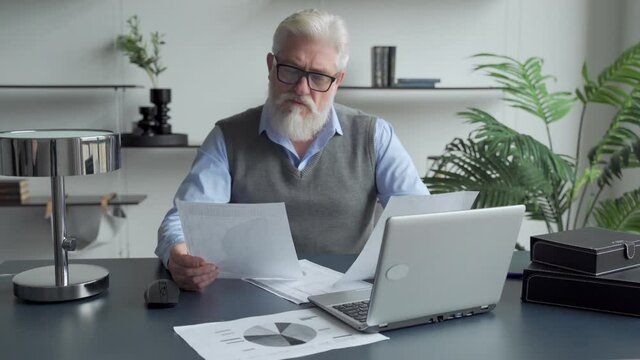 Senior mature business man working stressed and frustrated at office computer laptop desk looking tired and overwhelmed in job problems and overwork
