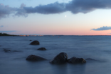 Fototapeta na wymiar Sunset over the sea. Stones on the foreground. Long exposure