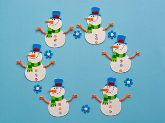 Happy Snowman toy made of paper, on a blue background.Handmade work. Snowflakes, space for text, shot from above, new year and Christmas Concept.