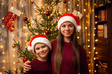 Happy siblings in similar clothes stand in bright decorated room and look to the camera. Family...