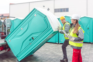 Worker loading portable toilets on truck