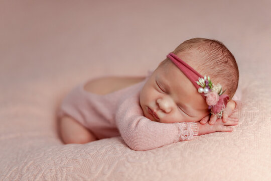 Sleeping newborn girl in the first days of life on pink blanket