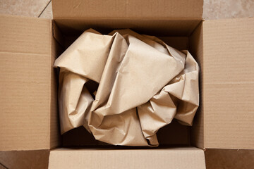 Crumpled wrapping craft brown paper in open after delivery paperboard box. Horizontal. Delivery, ecology, plastic free, resource overrun concept. Flat lay, top view, close-up