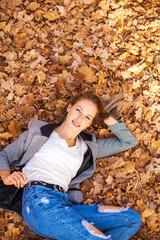 Portrait of a beautiful young woman on the background of autumn yellow leaves, outdoors