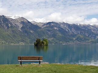 Bench facing towards picturesque lake and mountain scenery. Showing a tranquil and relaxing scene for recharging energy.
