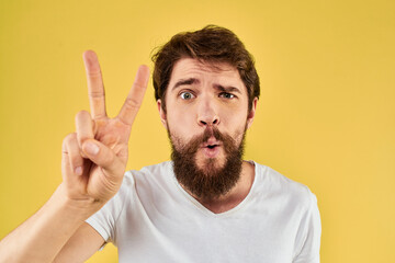 Bearded man emotions fun gesture with hands white t-shirt close-up yellow background