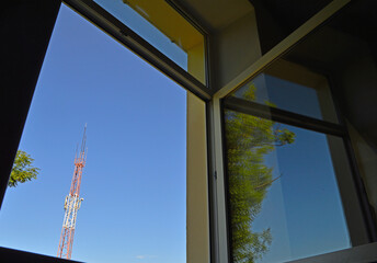 Open window overlooking the sky, tree and mobile phone antenna